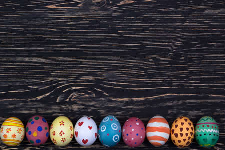 Painted Easter eggs on dark wooden background.の写真素材