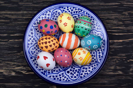 plate with Easter eggs on dark wooden backgroundの写真素材