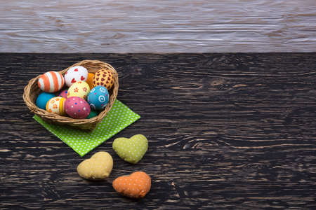 colorful easter eggs in a basket on dark wooden backgroundの写真素材