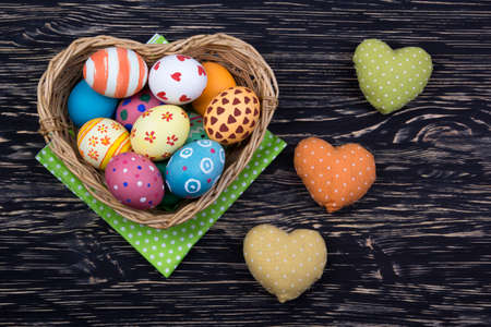 colorful easter eggs in a basket on dark wooden backgroundの写真素材