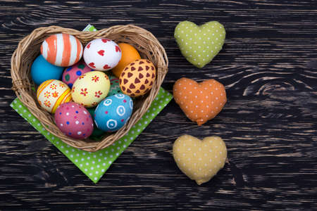 colorful easter eggs in a basket on dark wooden background