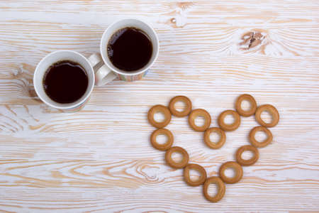 Two cups for tea with fragrant bagels on a white wooden backgroundの写真素材
