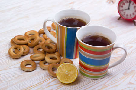 Two cups for tea with fragrant bagels on a white wooden backgroundの写真素材