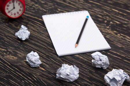 Crumpled paper balls with eye glasses and notebook on wood deskの写真素材