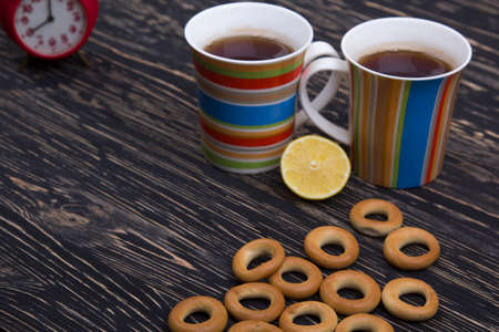 Two cups for tea with fragrant bagels on a black wooden background