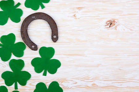 Fabric green clover leaves with horseshoe on light wooden background.の写真素材