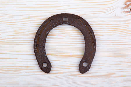 Old rusty horseshoe  on light wooden background.の写真素材