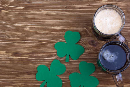 Dark Irish beer for St Patick's Day and clover leaves on the wooden tableの写真素材