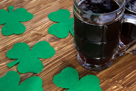Dark Irish beer for St Patick's Day and clover leaves on the wooden tableの写真素材