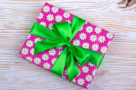 Gift box with ribbon on white wooden table