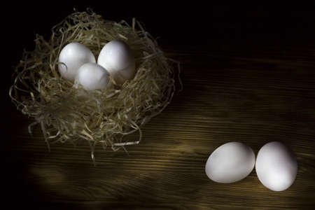 three eggs in the nest on a dark wooden background