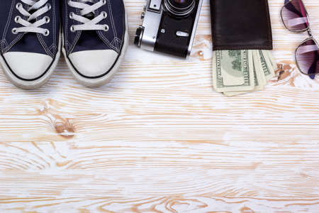 still life with sneakers, camera, sunglasses and wallet with dollars