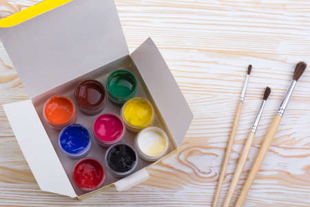 Gouache paints and brushes on light wooden backgound
