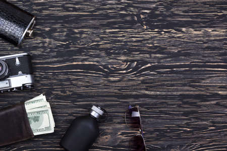 Set of men's accessories: wallet with dollard, flask, camera, sunglasses and perfume on wooden...