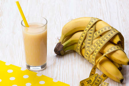 Banana juice with bananas and measuring tape on the wooden backgroundの写真素材