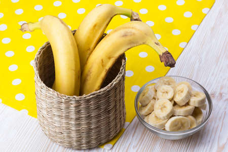 Sliced banana in bowl and bananas on wooden background.の写真素材