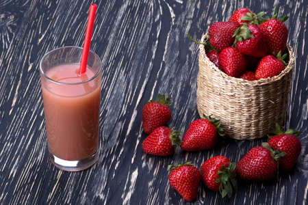 Juice and strawberries in a basket on the wooden deskの写真素材