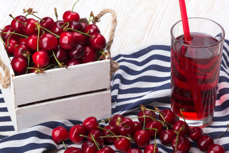 Juice and red cherries in a wooden box on wooden deskの写真素材