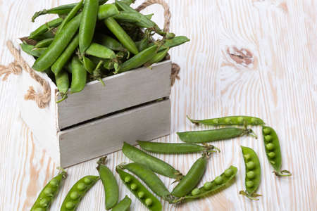 green peas in a wooden box on wooden desk