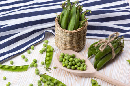 Fresh organic green peas in a basket on a wooden background.の写真素材