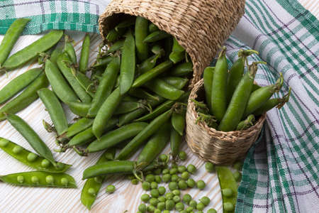 Fresh organic green peas in a basket on a wooden background.の写真素材