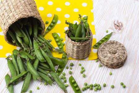 Fresh organic green peas in a basket on a wooden background.