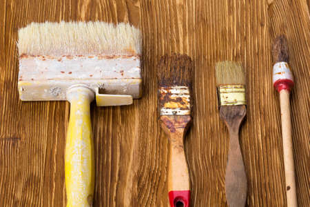 Old dirty vintage paint brushes on grunge wooden background in vintage style