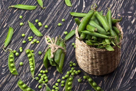 Fresh organic green peas in a basket on a wooden background.の写真素材