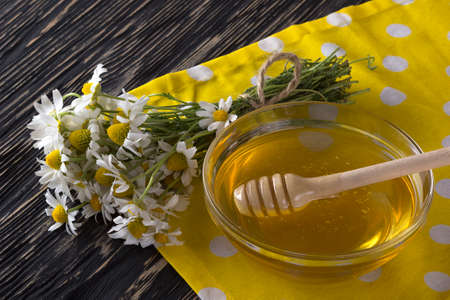 Fresh spring honey with chamomile flowers on wooden tableの写真素材