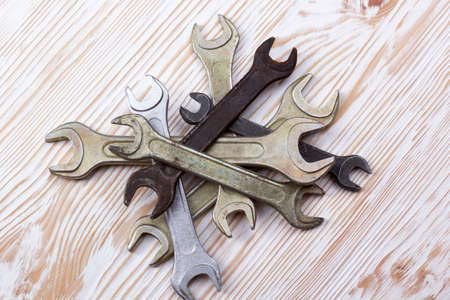 Set of wrenches in several different sizes on natural wooden background.