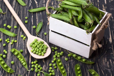 green peas in a wooden box on wooden deskの写真素材