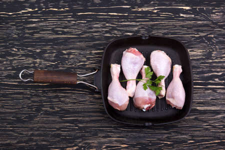 raw chicken drumstick in a pan on wooden tableの写真素材