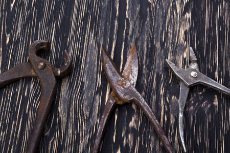 Heap of old instruments on wooden background. Pliers and scissors on wooden background.