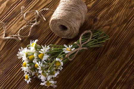 Beautiful bouquet of daisies with twine on wooden backgroundの写真素材