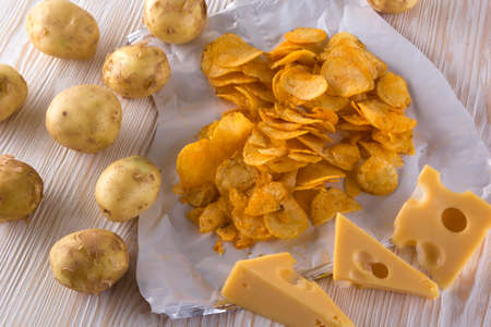 Potato chips, raw potato and cheese on wooden background.の写真素材