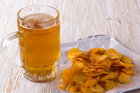 Potato chips and glass of beer on a wooden table.の写真素材