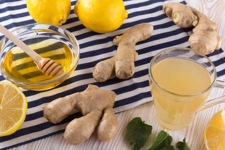 Cup of Ginger tea with lemon and honey on wooden background.
