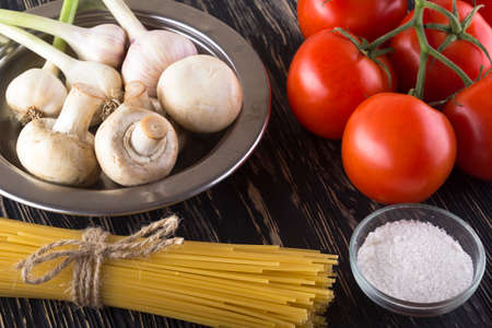Ingredients. Tomatoes, pasta salt basil and champignon on wooden background.の写真素材