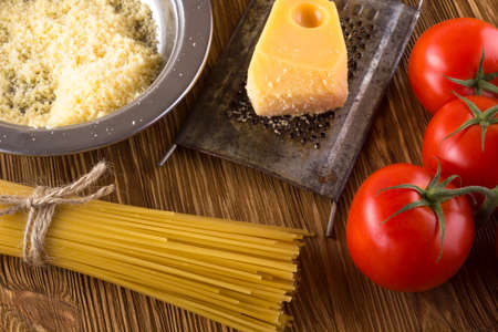 Pasta, tomatoes and grated cheese on wooden background.の写真素材