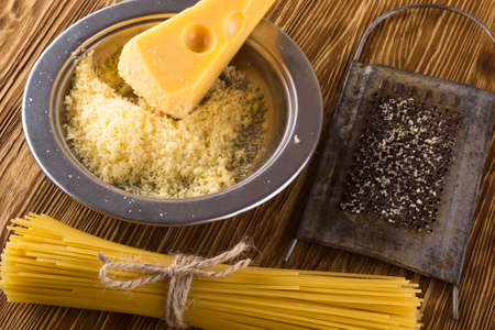 Pasta and grated cheese in a metal bowl on wooden background.の写真素材