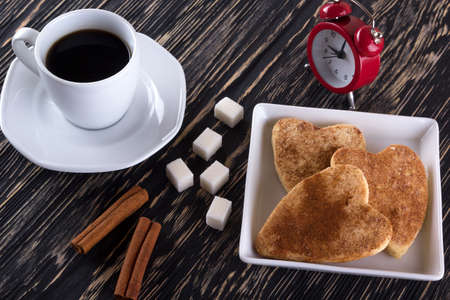 Cup of coffee with cinnamon cookies on wooden background.