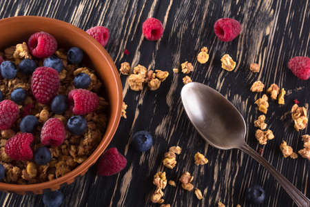 Muesli with fresh berries on wooden background.