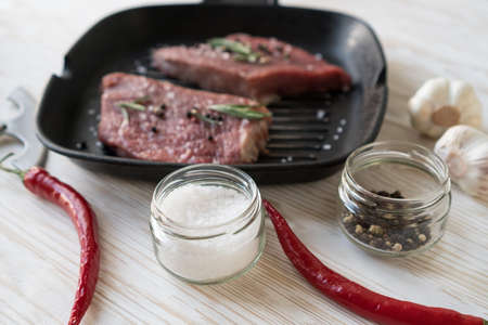 raw steak on cast iron frying pan with garlic and pepper.の写真素材