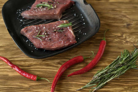pan of fresh meat with rosemary and pepper, top viewの写真素材