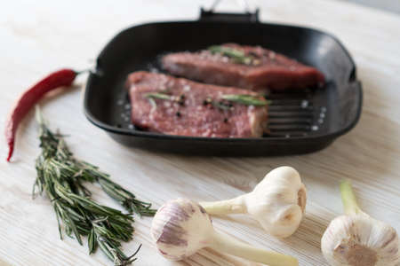 raw steak on cast iron frying pan with garlic and pepper.の写真素材
