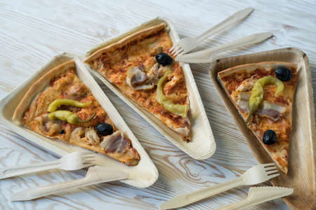 A slices of pizza is on a wooden plate.の写真素材