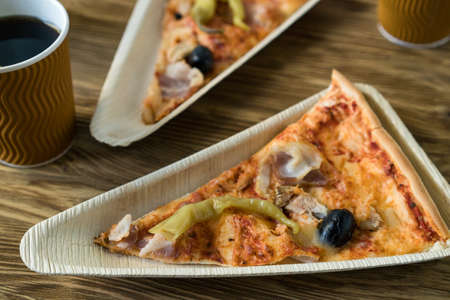 A slices of pizza is on a wooden plate.の写真素材