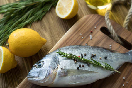 Raw fish cooking and ingredients. Dorado, lemon, herbs and spices.
