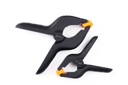 Two black construction clothespins of different sizes on a white background