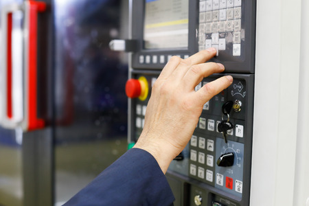 Operator working with CNC machining center using control panel. Selective focus.